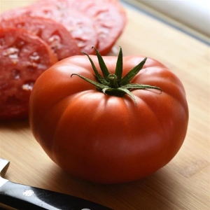 Red-ripened tomato sliced on a cutting board