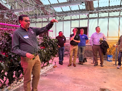 A speaker demonstrates indoor ag growing lighting setups to a group of visitors.